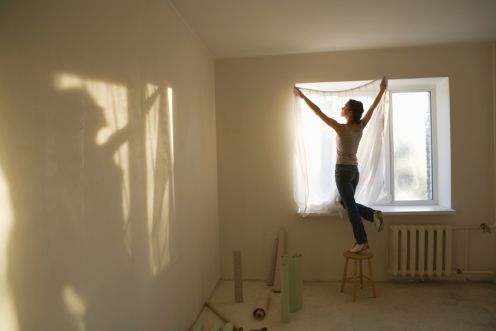 Woman fitting curtains in new apartment